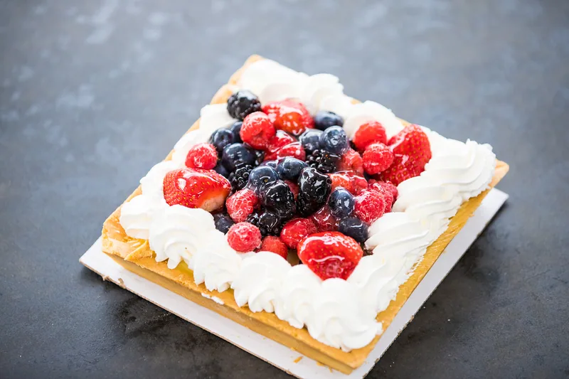 Square white cake topped with fresh berries