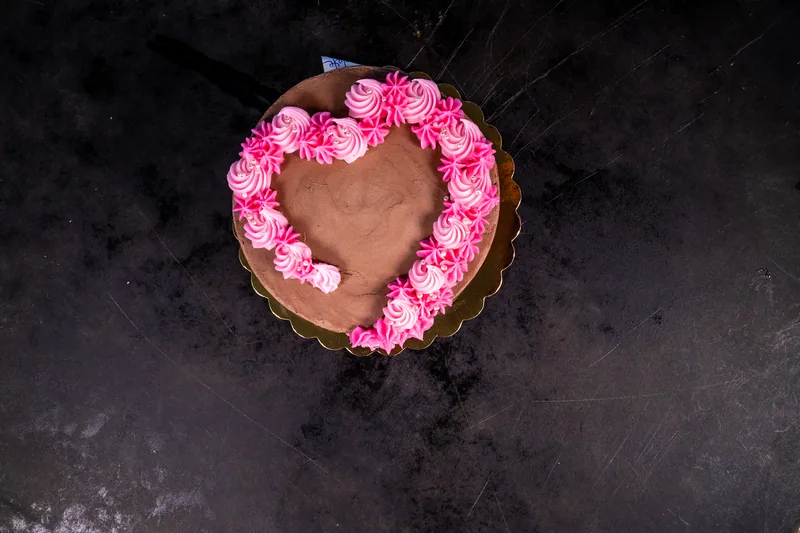 Heart-shaped chocolate cake with pink piped decoration